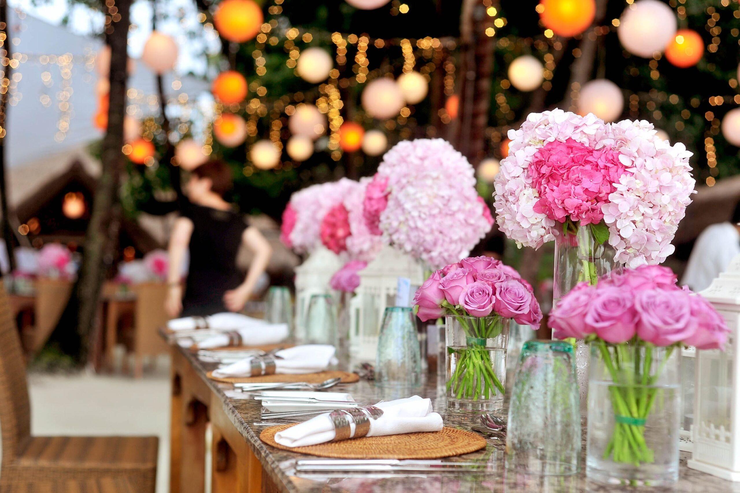Gedeckter Tisch für ein Hochzeitscatering mit rosa Blumen dekoriert